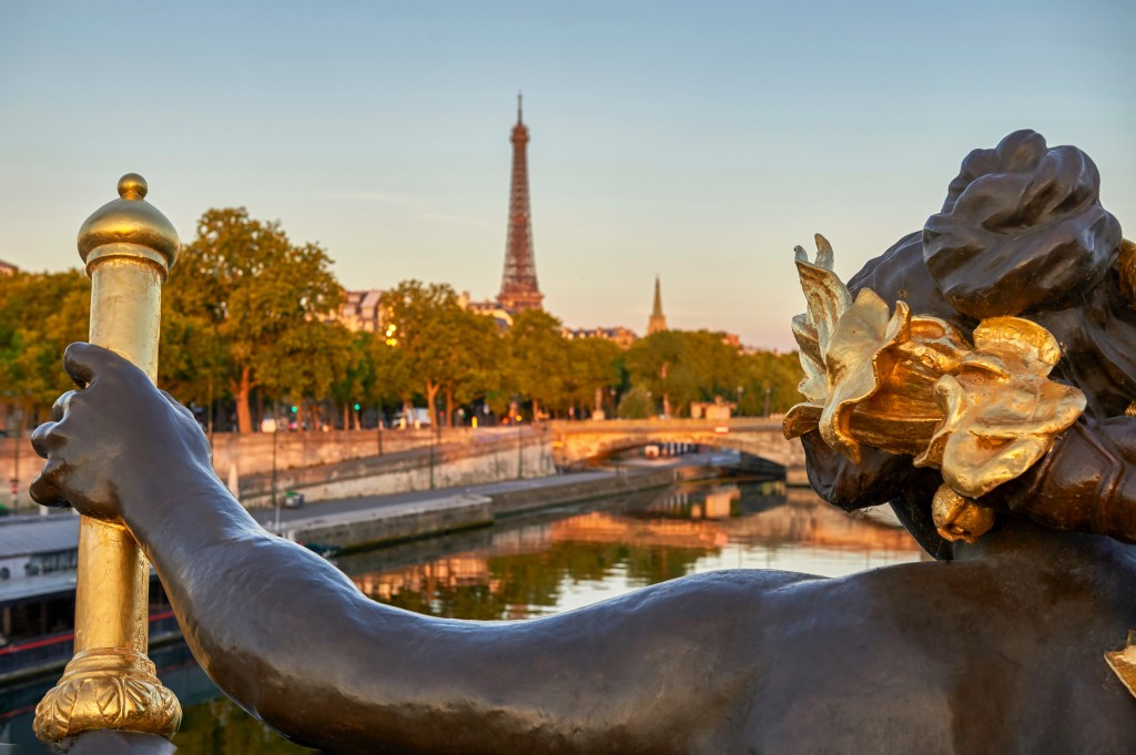 Laureled figure on Paris bridge over the Seine River with Eiffel tower in summer